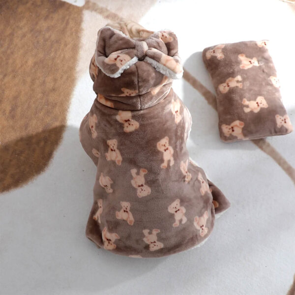 Cream French Bulldog sitting with back turned to camera while wearing brown hooded blanket with bears pattern